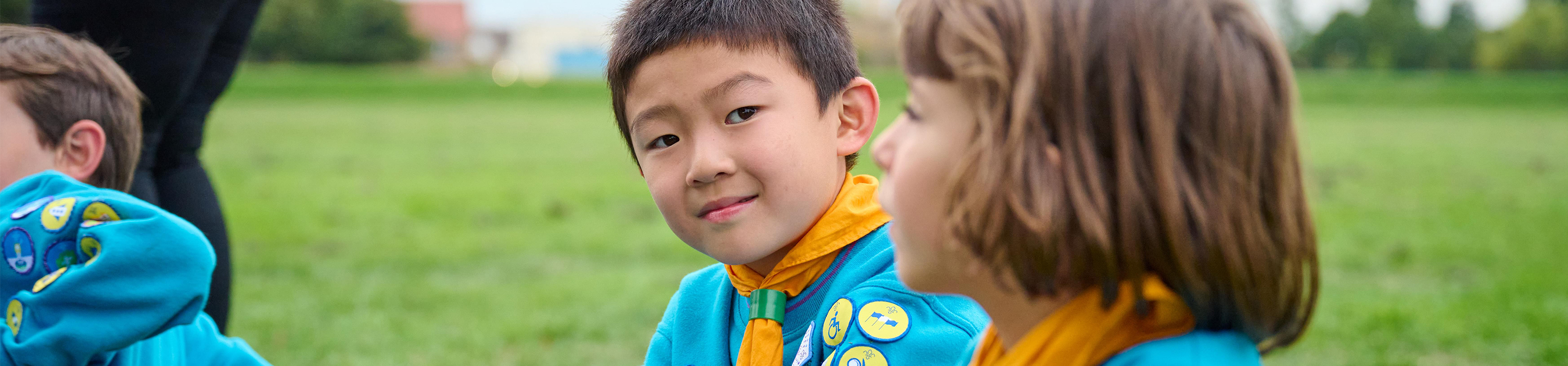 Children dressed in Beavers uniforms sitting on grass
